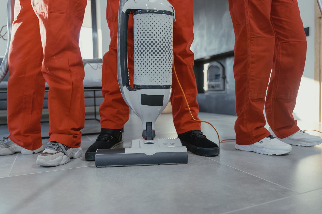 why-choose-us Team of professional cleaners in red uniforms using a vacuum cleaner indoors.